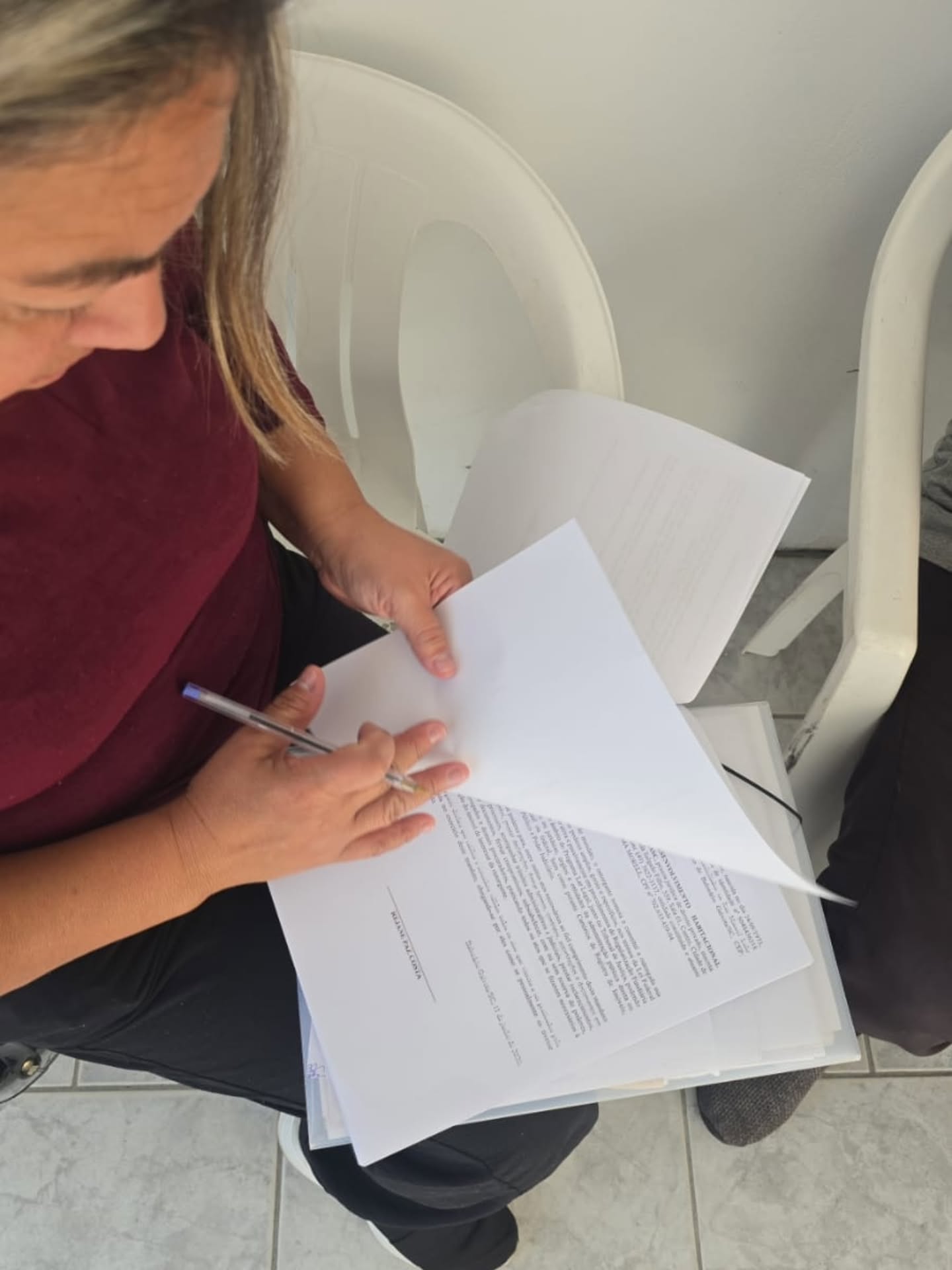 Moradora assinando documentos no colo